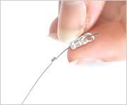 hand holding beading wire passed through a a silver plated crimp tube with loop.